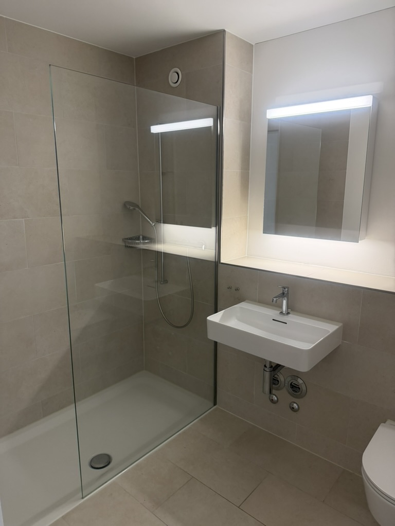 Dusche mit Glaswand und Lavabo