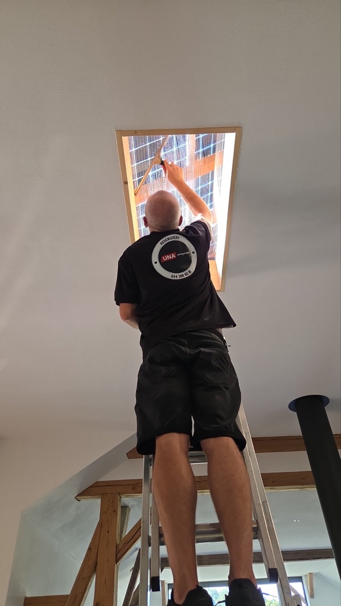 Mitarbeiter von UNA Reinigungen bei der Reinigung eines Dachfensters.