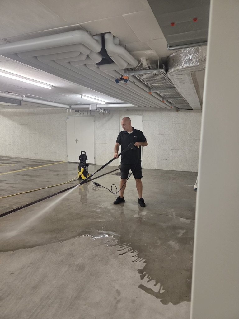 Mitarbeiter von UNA Reinigungen bei der Hochdruckreinigung eines Garagenbodens.