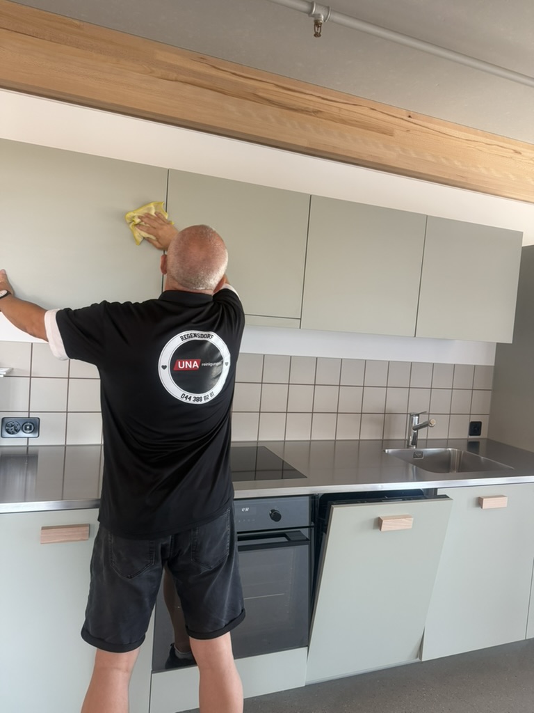 Mitarbeiter von UNA Reinigungen beim Reinigen der Fronten von Küchenoberschränken.