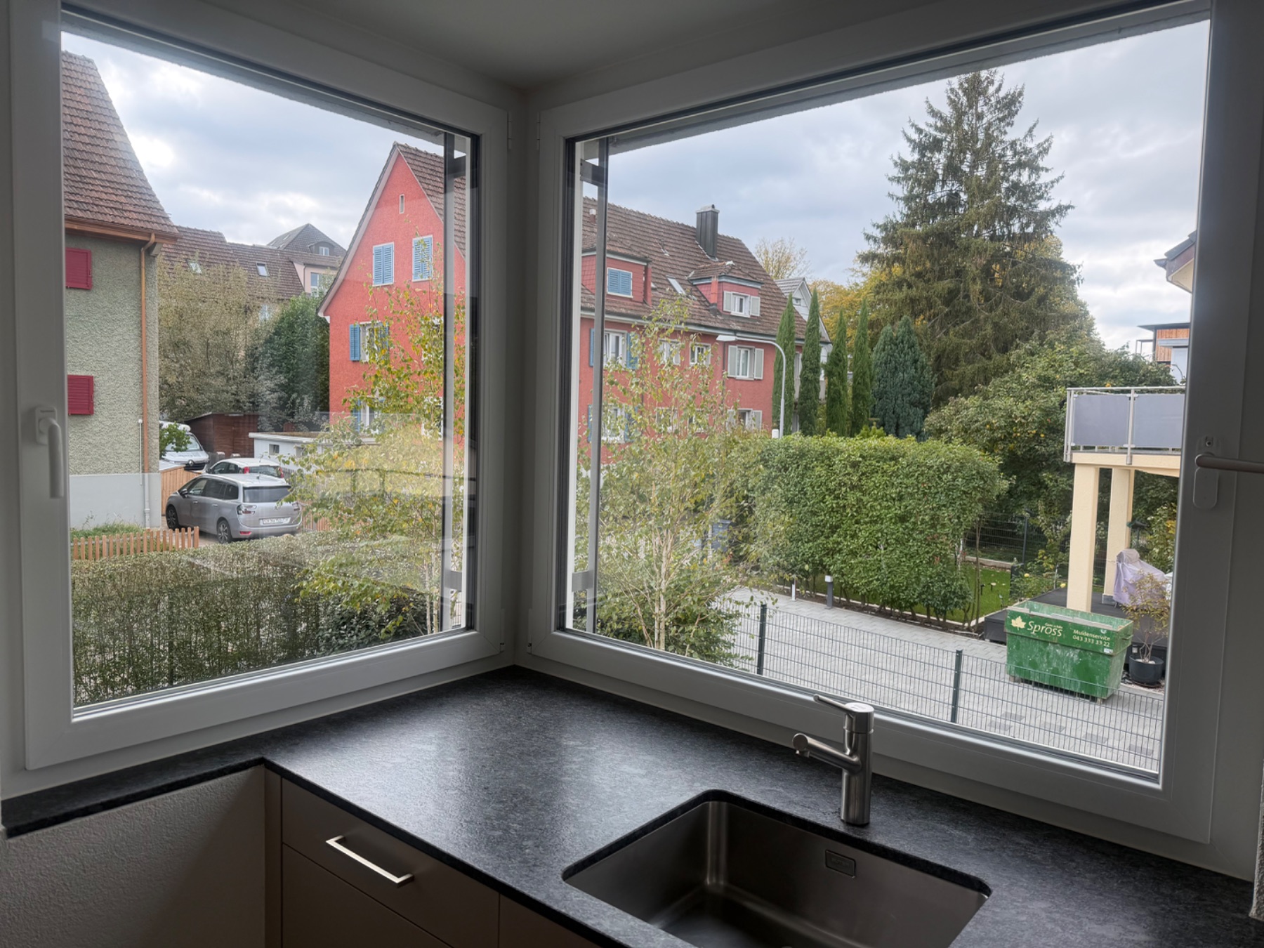 Fensterfront im Küchen-/Wohnbereich mit eingelassenem Spülbecken und Arbeitsfläche. Raum wirkt hell, Fussboden sauber.