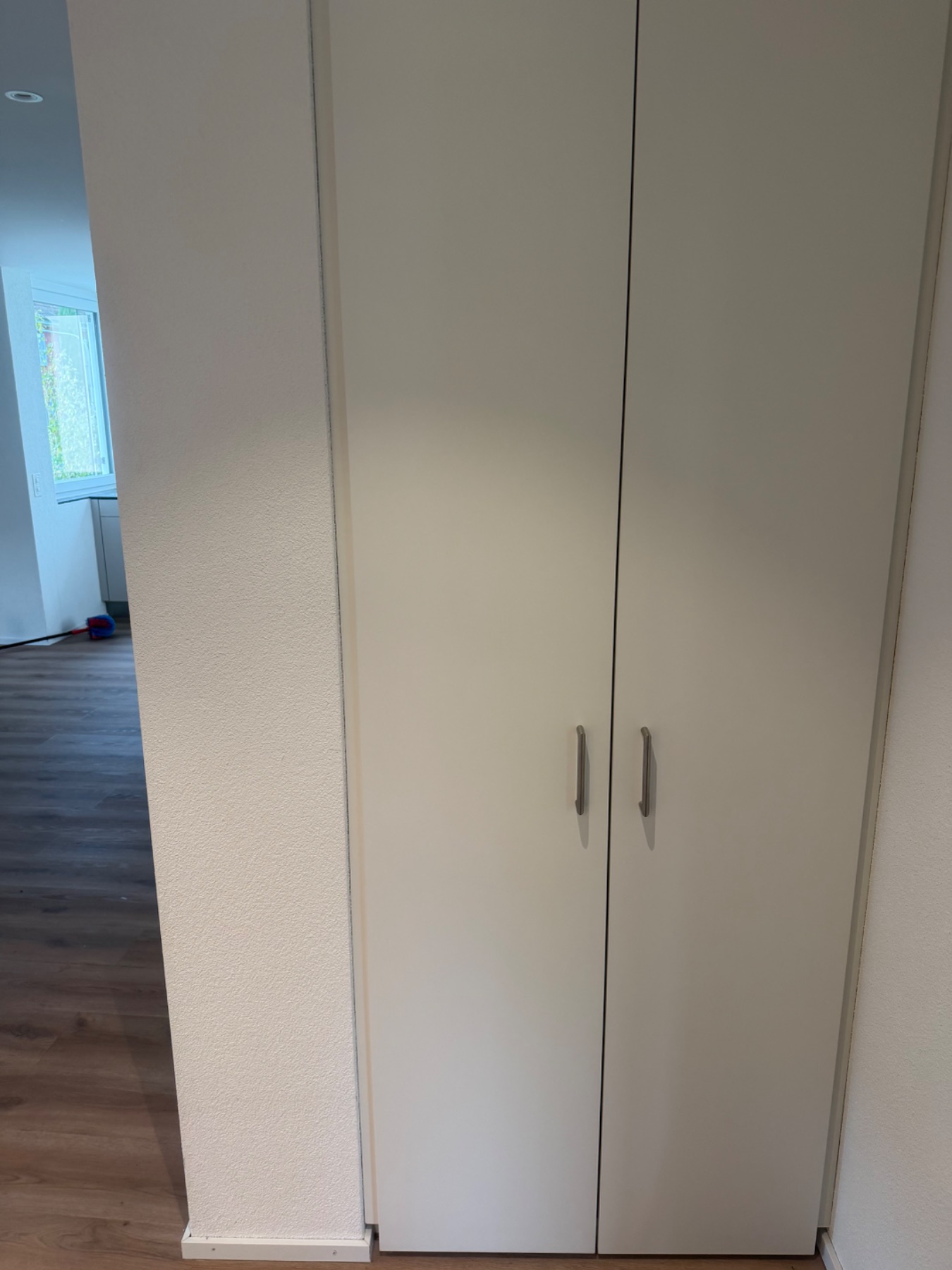 Schrank mit zwei Türen entlang der Wand. Sichtbar ist der saubere Bodenbereich neben dem Schrank.