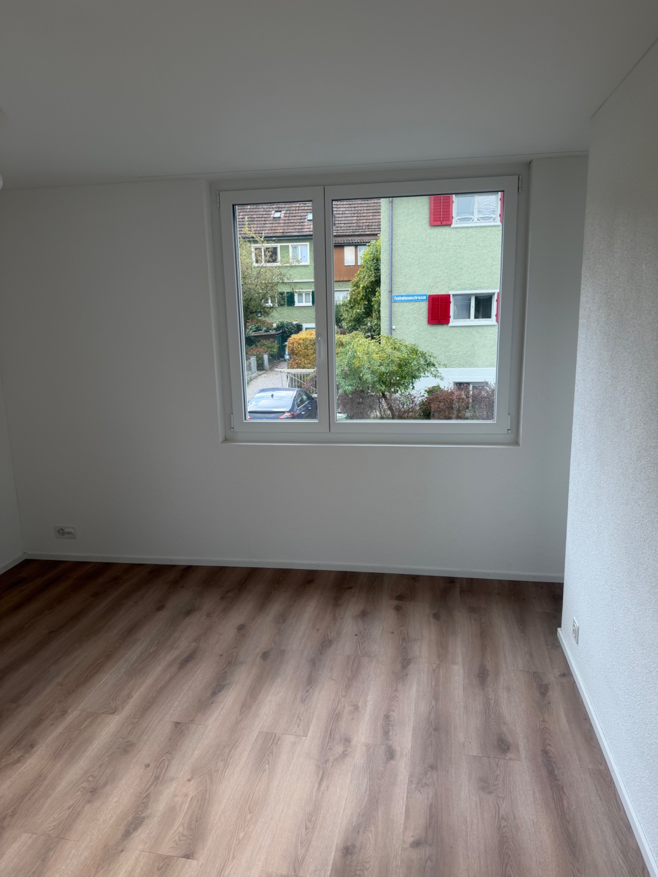Leerer Wohnraum mit Fenster und Parkettboden. Wände und Bodenflächen wirken gereinigt, der Raum ist frei.